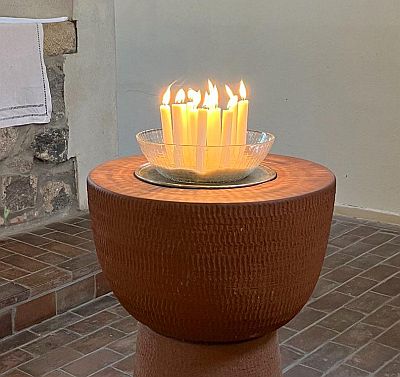 Im Taufstein der Frankenfelder Kirche steht eine Schale mit vielen brennenden Kerzen.