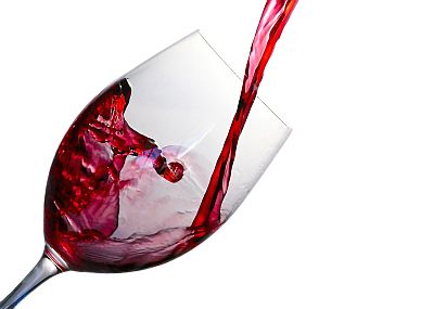 Roter Wein fließt in ein klares Weinglas und bildet darin einen Strudel.