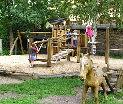 Abbidung: Kinder spielen auf einem Spielplatz im Grünen