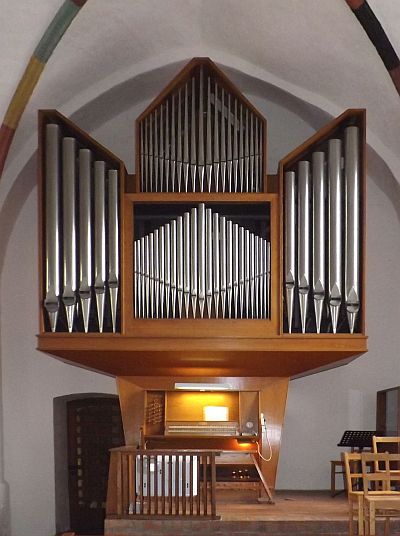 Eule-Orgel der St. Johanniskirche Foto: Auf einem gemauerten Podest erhebt sich en vierteiliger Orgelprospekt mit silberglänzenden Pfeifen. Zwei übereinander stehende Vierfuß-Pfeifenreihen, deren größte jeweils in der Mitte steht, werden rechts und links von zwei Feldern mit jeweils fünf Achtfuß-Pfeifen flankiert, deren größte Pfeife jeweils außen angeordnet ist und die dem Prospekt die Gestalt eines Engels verleihen. Unter den Pfeifenregalen ist der Spieltisch angeordnet. Der Organist sitzt mit dem Rücken zum Altar bzw. zum Kirchenschiff.